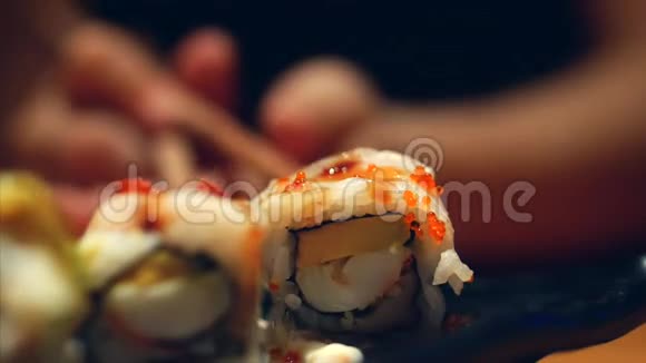 手拿棍子的小女孩拿寿司概念中国棒寿司卷在一个黑暗的盘子视频的预览图