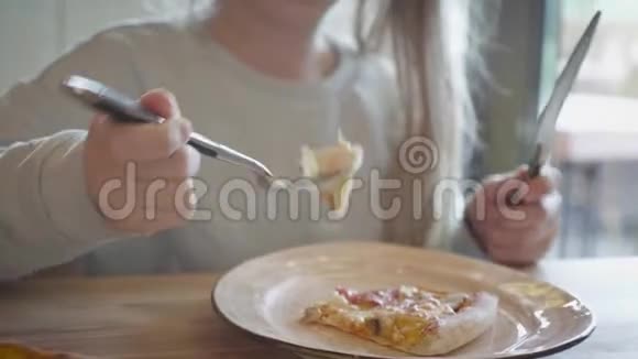 一个有辫子的年轻女孩正在吃一块披萨可爱快乐的小女孩笑着咬着一大块新鲜的视频的预览图