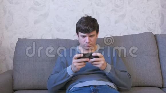 专注的人坐在沙发上用手机玩游戏视频的预览图
