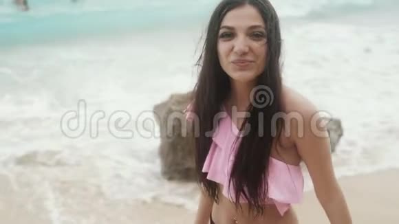慢动作快乐微笑的美丽女孩的肖像穿着泳衣在海滩上休息稳定的镜头视频的预览图