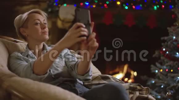 迷人的女人在圣诞夜坐在泡芙椅上自拍视频的预览图