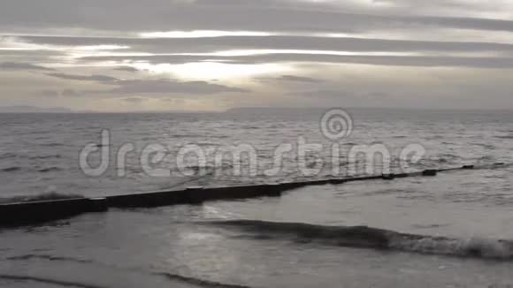灰色的海浪拍打海岸在一个部分阴天的下午的天空视频的预览图