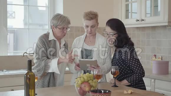 女人在平板电脑上给她的朋友看照片三个中年成熟女性群体交流聊天支出视频的预览图
