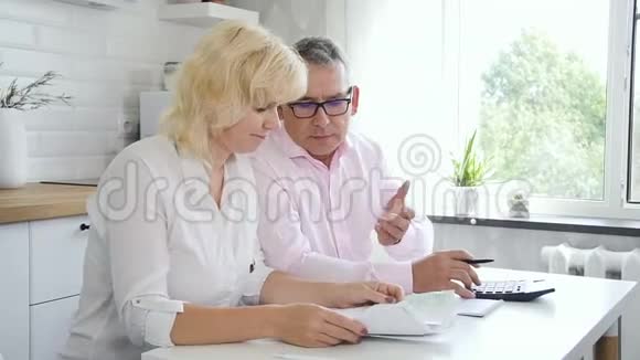 高级丈夫和成熟妻子在厨房计算家庭财务视频的预览图