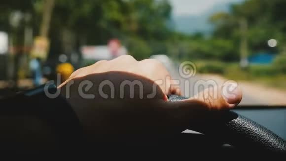 漂亮的车内特写男手握着方向盘沿着模糊的美丽阳光大道行驶着绿树成荫视频的预览图