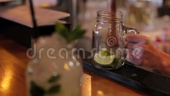 酒保用勺子捏柠檬汁在酒吧的特写镜头里煮莫吉托视频的预览图