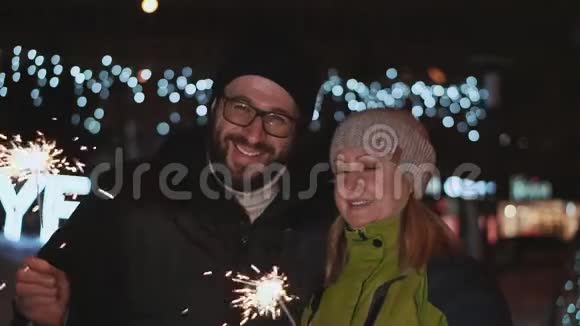 幸福的夫妻夫妻在街上庆祝新年他们手里拿着火花对着视频的预览图