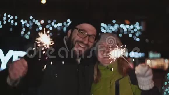 幸福的一对夫妻庆祝新年冬天在外面他们手里拿着火花对着视频的预览图