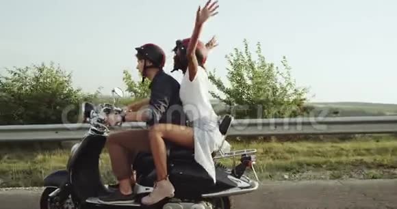 一个年轻的女人和一个男人戴着头盔骑着摩托车上路视频的预览图