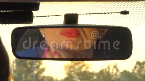 女孩坐在车里照镜子她触摸下巴确保嘴唇上的口红很好女孩进入决赛视频的预览图