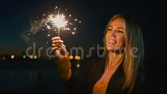 女人拿着燃烧的火花开朗的年轻女子手里拿着两颗星星在户外庆祝新年视频的预览图