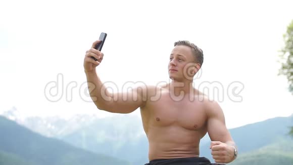 男人拿着智能手机在山上的户外自拍视频的预览图
