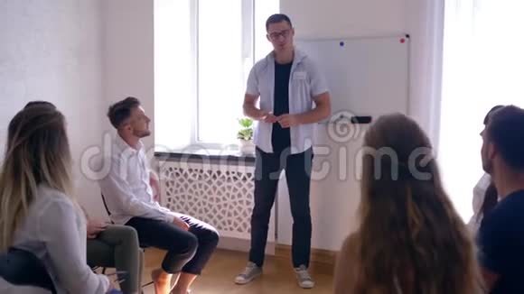心理训练男人心理学家领导小组的人在黑板上说和写单词动机视频的预览图