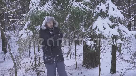 一个人从雪中擦手那个人冻僵了站在森林里视频的预览图