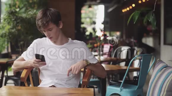 年轻人用手机上网方便触摸在咖啡馆发送短信帅哥在里面聊天视频的预览图