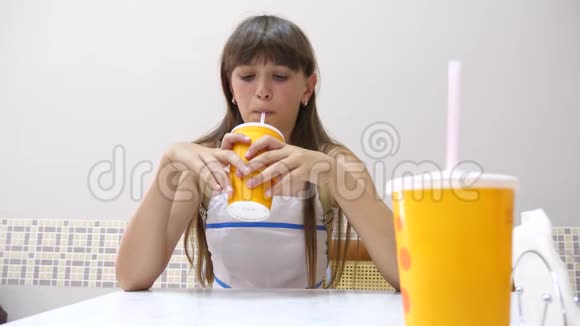 女孩坐在咖啡馆的桌子上喝着美味的鸡尾酒微笑着视频的预览图