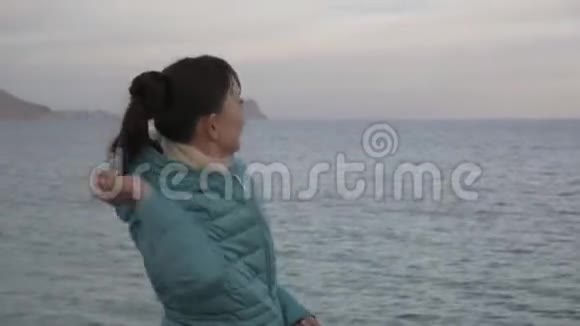 孤独寒冷海滩的女人白种人女人向平静的大海投掷石头的中锋视频的预览图