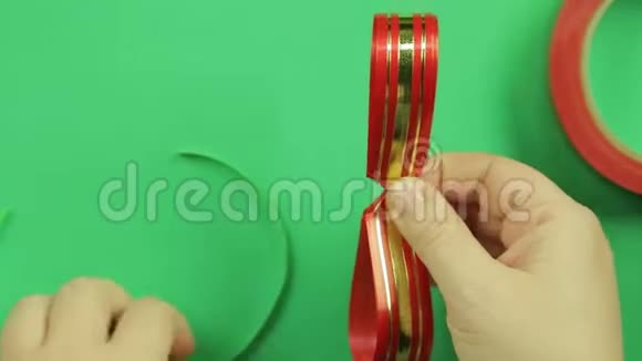 女人双手用绿色胶带绑起一块空白的红丝带做礼物蝴蝶结绿色背景视频的预览图