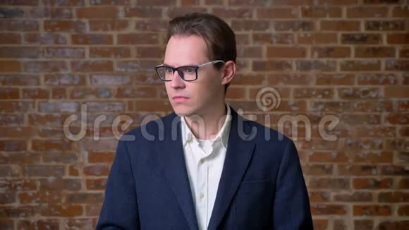 穿深色西装的白种人的宾果标志眼镜办公室外观砖背景视频的预览图