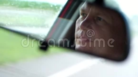 特写镜头在汽车后视镜里司机脸是可见的他认真地看着路下雨雨刷视频的预览图