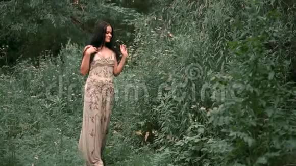 一个穿着银色刺绣的灰色连衣裙留着黑色长发的女孩野生森林用手触摸鲜花视频的预览图
