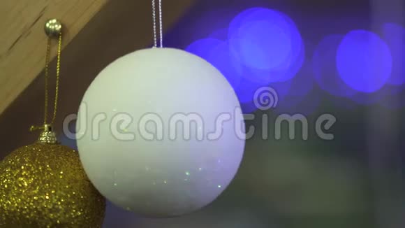两个白色和金色的圣诞树玩具挂在一根木梁上背景模糊摄像机向左移动慢慢视频的预览图