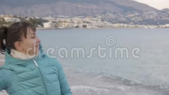 孤独寒冷海滩的女人白种人女人向平静的大海投掷石头的肖像视频的预览图