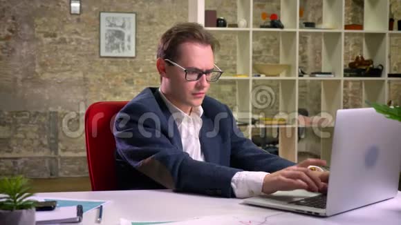 无聊而忙碌的工作中白种人的男性正在打电话坐在办公室里视频的预览图