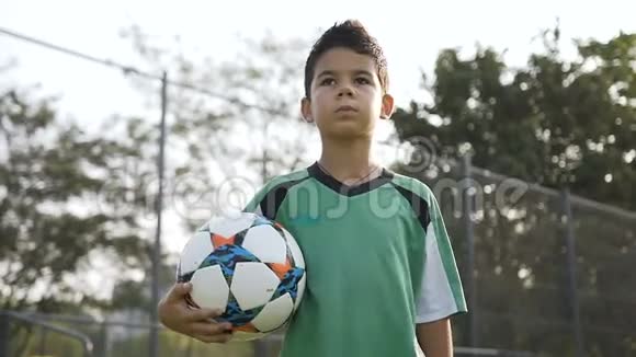 运动男孩手里拿着足球在球场上行走的肖像视频的预览图