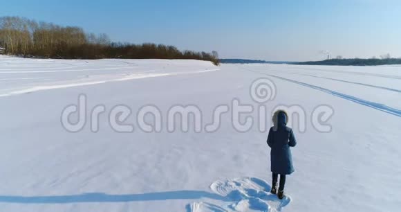 空中镜头奔跑的女人在冬天的风景冻结的河流与森林和城市的景色与视频的预览图
