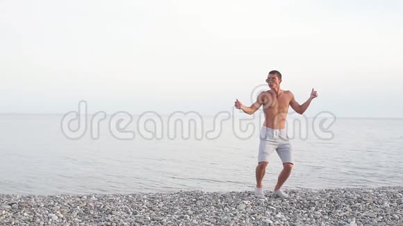 年轻苗条美丽的男性在海滩上跳舞暑假玩得开心心情积极视频的预览图