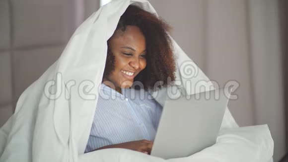 幸福的女人躺在家里的床上视频聊天视频的预览图