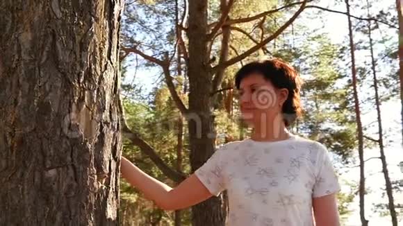 一个年轻的女人在树上走来走去摸着他的手在森林的背景上视频的预览图