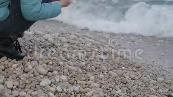 孤独寒冷海滩的女人一位迷人的白种人女子在海滩上水边玩石头视频的预览图