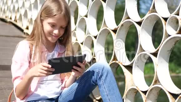 在公园玩平板电脑小女孩在大自然中使用户外智能手机视频的预览图