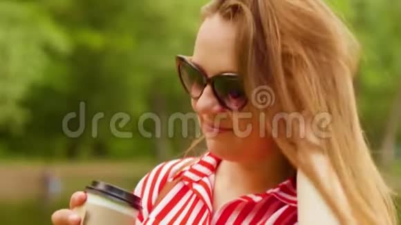 夏天女孩站在公园里喝塑料杯里的咖啡近距离射击视频的预览图