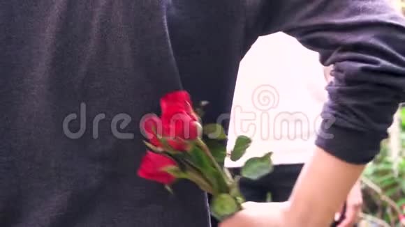 男人背着红玫瑰把玫瑰送给女人情人节礼物概念视频的预览图