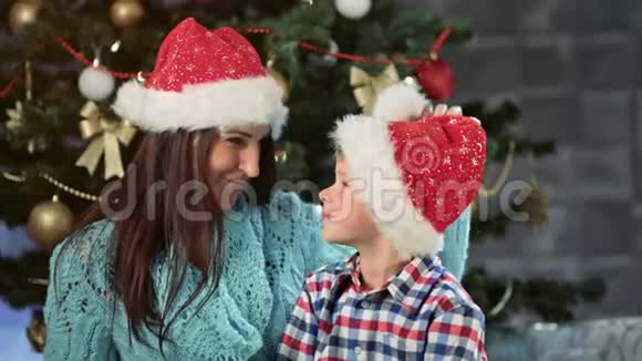 快乐的妈妈和可爱的小儿子一起在树旁享受圣诞节视频的预览图