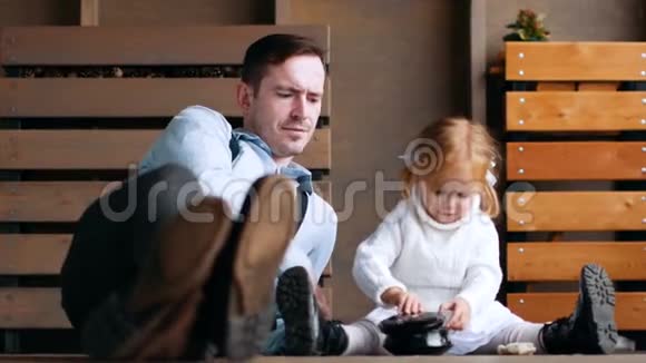 父亲和女儿坐在地板上玩视频的预览图
