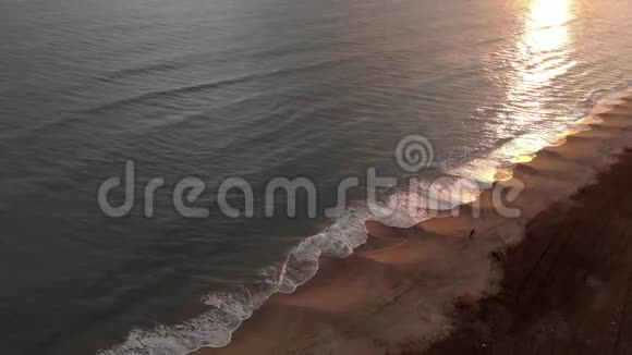 空中俯瞰金色的日落海浪拍打着海岸水面上有美丽的倒影远处有一个视频的预览图