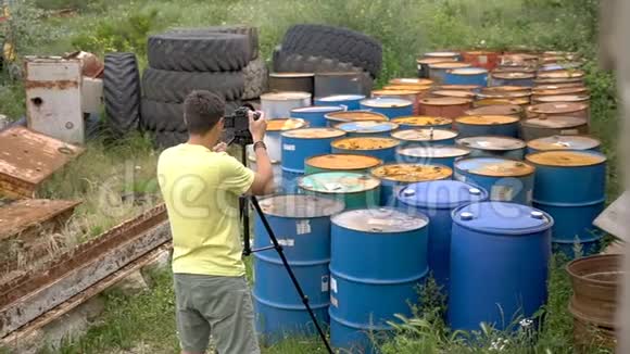 录像员把旧的脏油桶移走使用三脚架视频的预览图