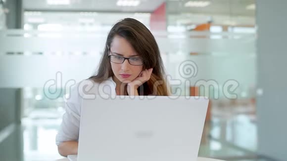 那个女孩在一间宽敞明亮的办公室里用笔记本电脑工作视频的预览图