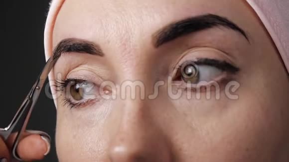 眉毛护理漂亮的女人用剪刀剪下多余的眉毛特写镜头视频的预览图