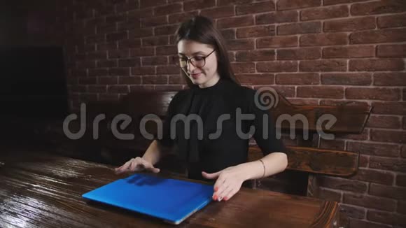 办公室里戴眼镜的年轻女孩在笔记本电脑键盘上打印文本视频的预览图