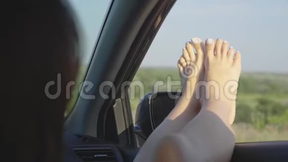 一个女孩在开着窗户的车里伸出双腿年轻女性喜欢坐车旅游旅游理念生活方式视频的预览图