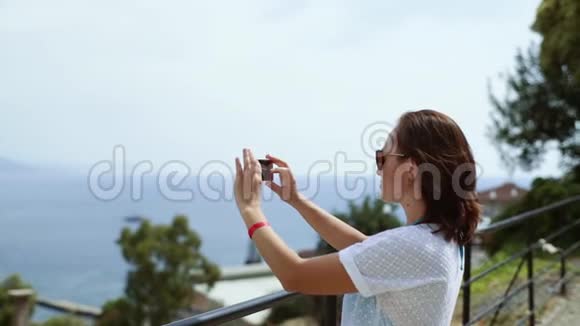 一位穿着白色连衣裙的女游客在智能手机上从鸟瞰拍摄城市的照片城市的景色视频的预览图
