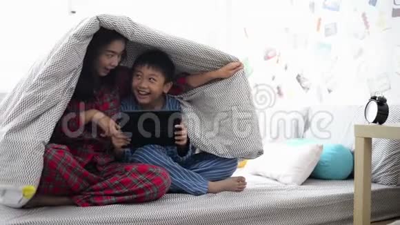 母亲和儿子一起在毯子下面的平板电脑上看电影视频的预览图
