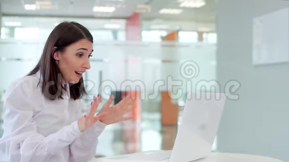 办公室里的女孩拿着笔记本电脑仔细地看着显示器开始高兴地尖叫视频的预览图
