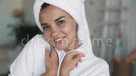 穿着浴袍头上戴毛巾的女孩的肖像照相机微笑慢动作视频的预览图