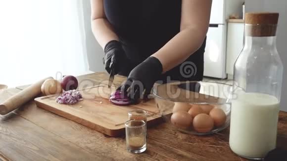 用手套在木制烹饪板上切洋葱视频的预览图